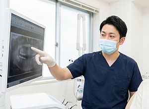 レントゲン写真を指差す歯科医師